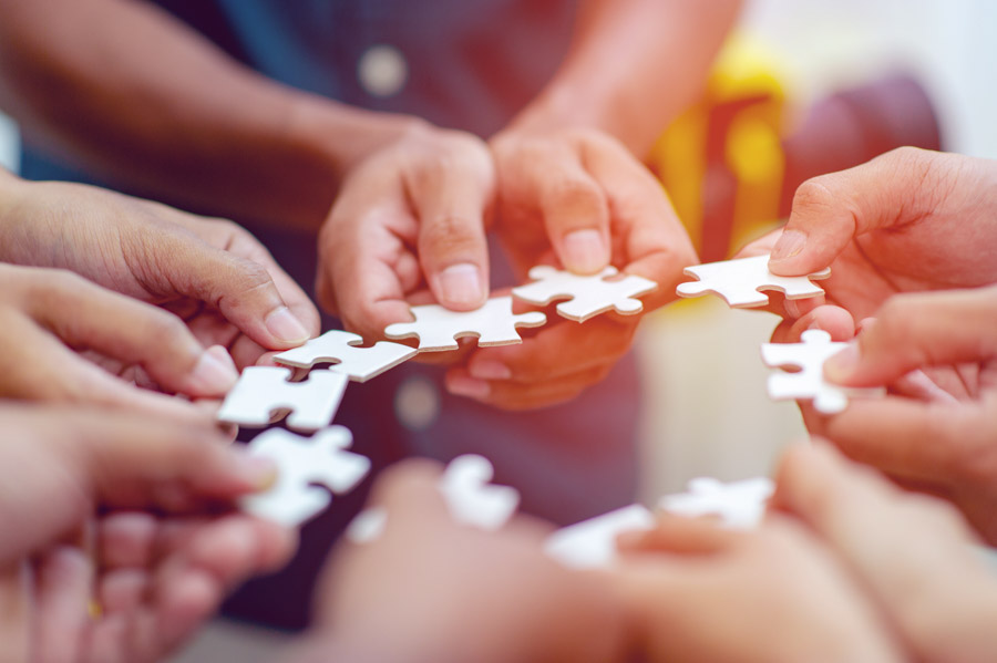 Menschen halten Puzzleteile aneinander in einem Kreis