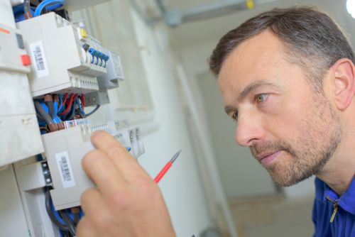 Ein Elektriker arbeitet am Sicherungskasten. Renovierungs-Arbeiten an der Elektrik sind i.d.R. Vermieter-Sache.