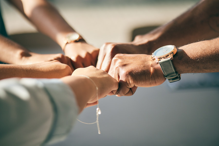 Menschen, die Ihre Hände zu einem Fistbump zusammenführen symbolisch für den Zusammenhalt des Mieterhilfe e.V.